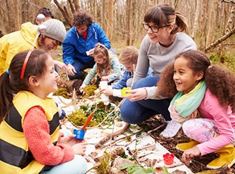 A group of children and adults are making bush art together