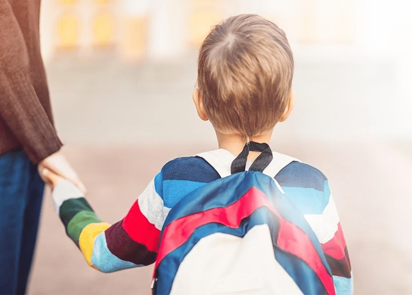 Very young boy, wearing a backpack, holds his mother hand