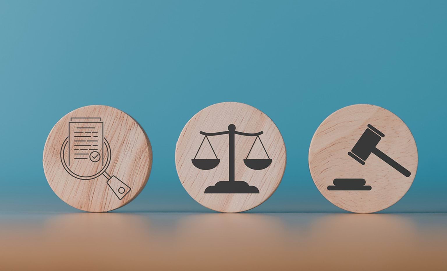 Wooden blocks sit on a table each with a symbol representing, investigation, justice and legal decision.