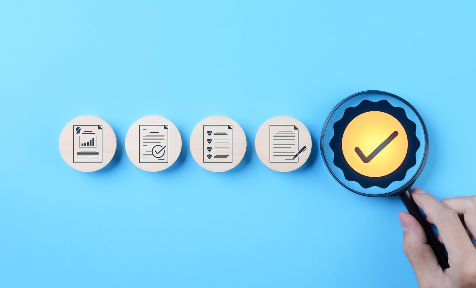 Hand holding magnifying glass over checkmark symbol, alongside icons representing quality control, certification, and assurance on blue background