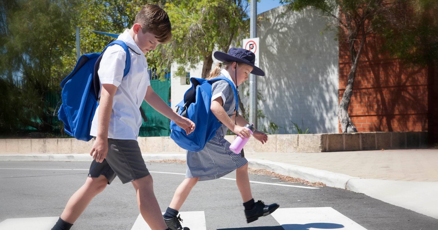Two small children in school uniform walking to school